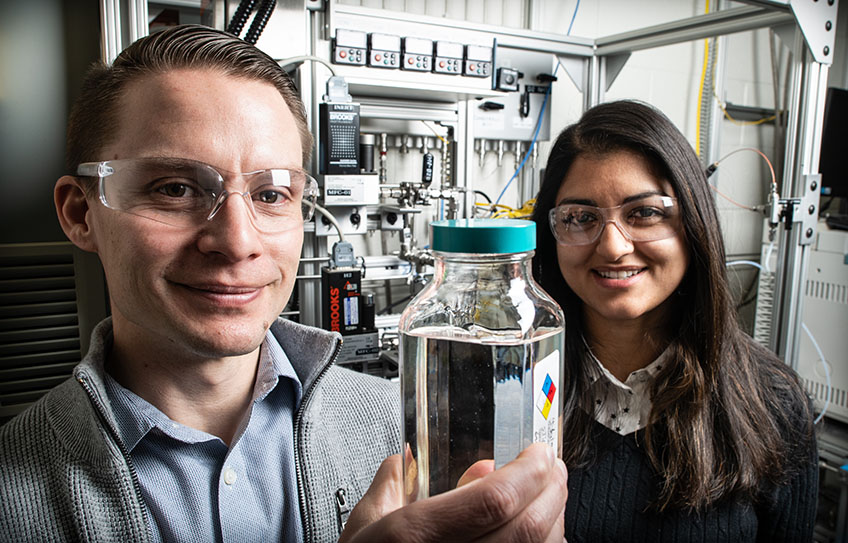 Derek Vardon and Nabila Huq display a container of high-performance ether diesel bioblendstock manufactured at NREL. Credit: Dennis Schroeder/NREL